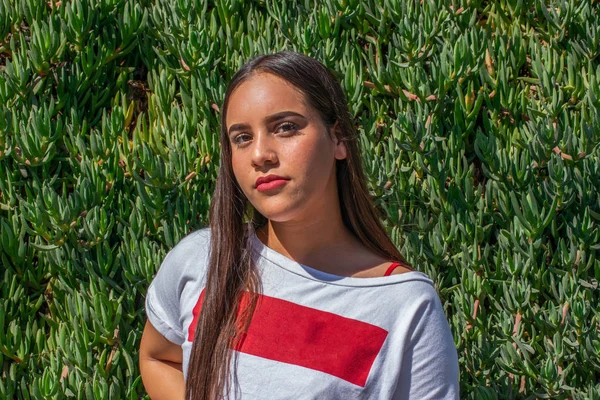 Una mujer joven de gran tamaño, de apariencia americana o latina. frente al fondo de las plantas verdes —  Fotos de Stock