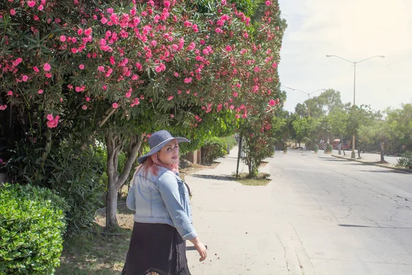 幸せな女性で帽子歩く脇ピンクの花の木 — ストック写真