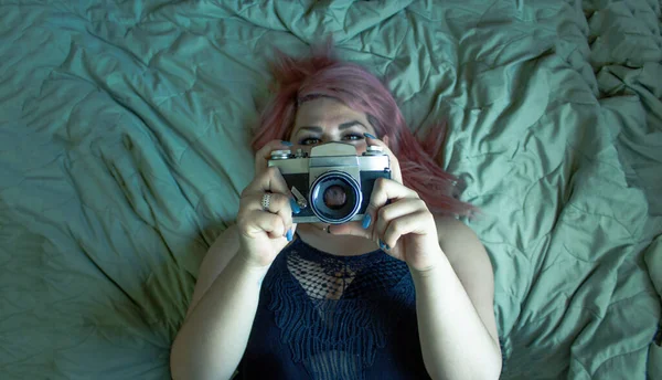 粉色头发的女人躺在床上 使用旧相机 — 图库照片