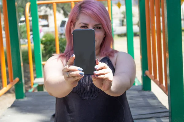 ピンクの髪の女性が携帯電話を見せ — ストック写真