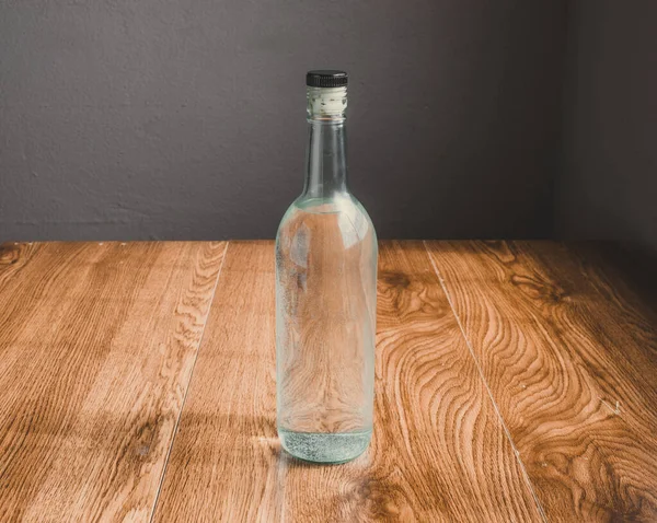 Temiz likörlü bir şişe. Mezcal, kristal tekila ya da votka gibi. Tahtalar üzerinde,