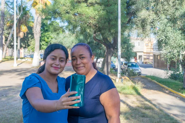 İspanyol anne ve kızı parkta selfie çekiyorlar.