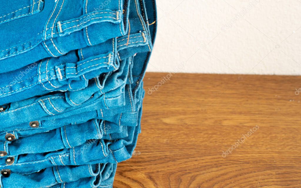 closeup of stack of blue jeans. in store on wooden shelf