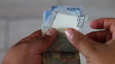 Close-up of hands counting a stack of mexican 500 and 1000 pesos bills