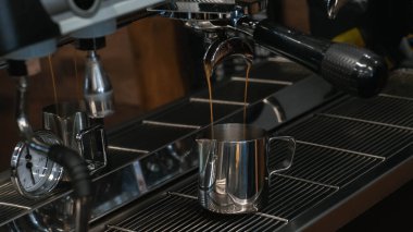 Kahve makinesinde kahve yapma süreci. Kahve tutucudan sürahiye dökülüyor..