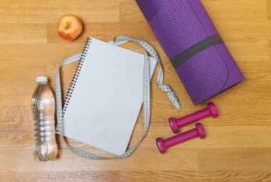 Yoga mat, Not defteri, apple, halter ve şişe suyu ahşap zemin üzerinde. Kopya alanı ile üstten görünüm.