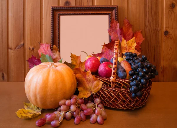 Fruits frais dans le panier, citrouille et cadre photo sur table en bois — Photo