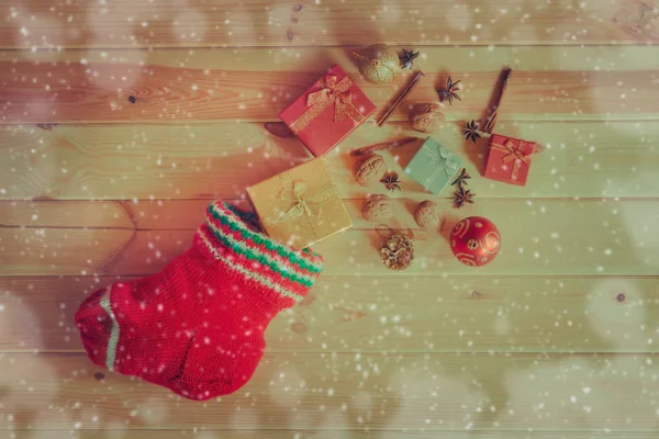 Red christmas stocking with gifts, ball, spices and walnuts. — Stock Photo, Image