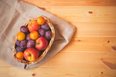 Elma ve Erik ahşap arka plan ile sepet. Üstten görünüm, kopya alanı.