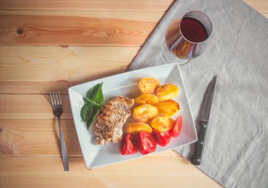 Bir bardak kırmızı şarap ve masada kavrulmuş patates ile ızgara domuz. Üstten görünüm, kopya alanı.