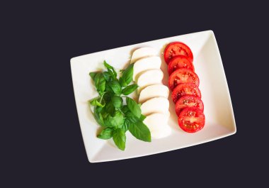 Yeşil fesleğen yaprağı, biçim ve renk koyu arka plan üzerinde İtalyan bayrağı olgun domates ve mozzarella peyniri. Üstten görünüm, kopya alanı.