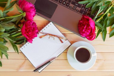Boş defter, gözlük, laptop klavye, ahşap masa kahve ve kırmızı Şakayık çiçekleri fincan. Üstten Görünüm, kopya alanı.