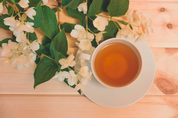 Fincan yeşil çay ve tahta masaya beyaz Yasemin çiçek. Seçici odak. 