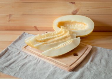 Yarım olgunlaşmış kavun ve kesme tahtası üzerinde olgunlaşmış kavun dilimleri