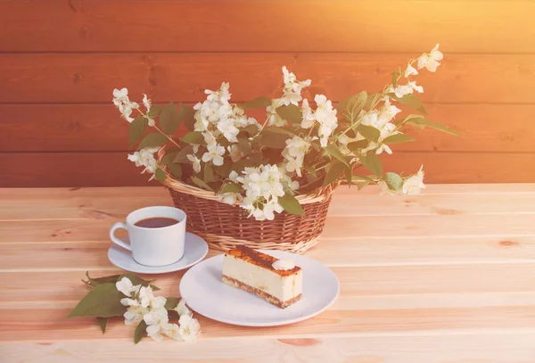 Copa de café y pastel cerca de la cesta de mimbre con flores de jazmín —  Fotos de Stock