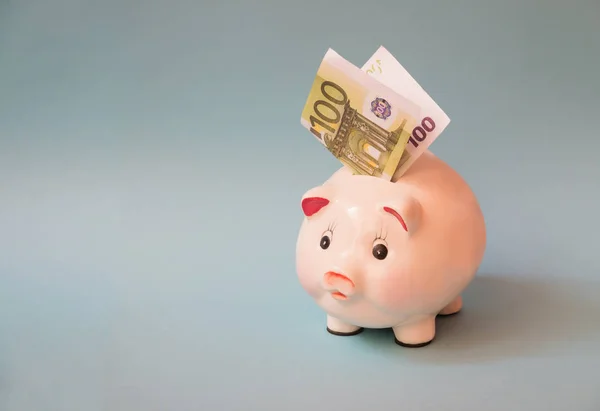 Piggy bank with euro banknote inserted in slot, on blue background. Financial planning, savings and investment concept. — Stock Photo, Image