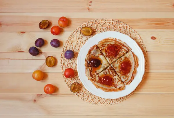 Crêpes avec confiture de prunes maison et prunes fraîches près de la table en bois . — Photo