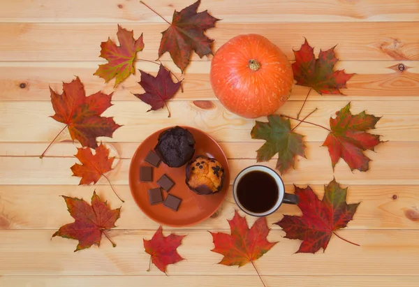 Tasse de café, feuilles d'érable d'automne, citrouille et muffins sur table en bois . — Photo