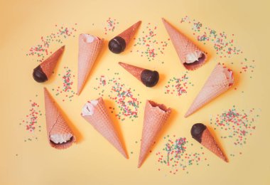 Vanilyalı dondurma konileri ve şeker den yapılmış gıda deseni sarı arka plan üzerinde yıldız serpin.