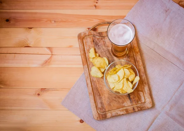 Vaso de cerveza con papas fritas sobre fondo de madera . — Foto de Stock