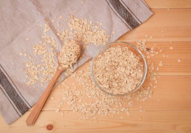 Haddelenmiş yulaf veya yulaf gevreği cam kase ve tahta kaşık. Üstte görüntü.