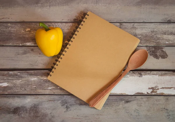 Quaderno aperto per note e peperone giallo su fondo legno invecchiato . — Foto Stock