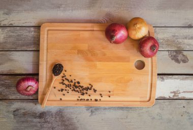 Kesme tahtası, taze soğan ve karabiber yaşlı ahşap arka plan üzerinde. 