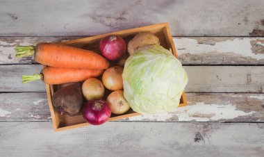 Yaşlı ahşap arka planda ahşap tepsi üzerinde çeşitli taze sebzeler.