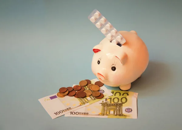 Skarbonka, tabletki w blistrze i gotówka euro na niebieskim tle. — Zdjęcie stockowe
