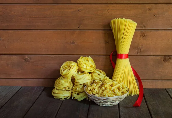 Verschiedene Arten roher Pasta auf gealtertem Holztisch. Ansicht mit Kopierraum. — Stockfoto