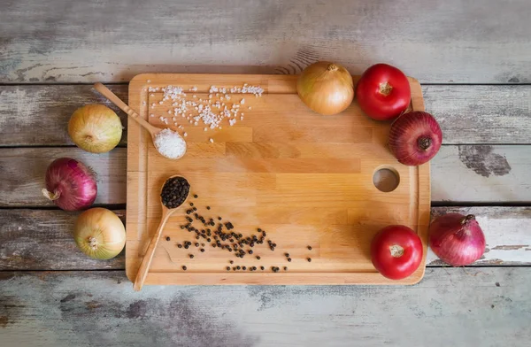 Tagliere, condimenti, pomodori freschi e cipolle su fondo di legno invecchiato . — Foto Stock