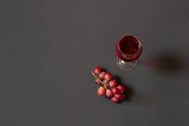 Kırmızı şarap ve koyu arkaplanda mor üzüm dalı. Üst görünüm, alanı kopyala.