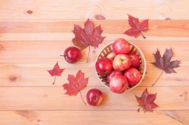 Tahta masada kırmızı elmalı sepet, sonbahar akçaağaç yaprakları. Üst görünüm, alanı kopyala.