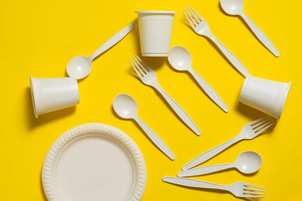 disposable biodegradable fork, spoon, glass and plate of corn starch on a yellow background. environmentally friendly dishes. isolate. place for text. modern ecoplastics replacement
