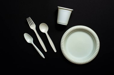 Tek kullanımlık ayrıştırılabilir çatal, kaşık, cam ve siyah arka planda bir tabak mısır nişastası. Çevre dostu yemekler. İzole et. mesaj için yer. eko plastik değiştirme