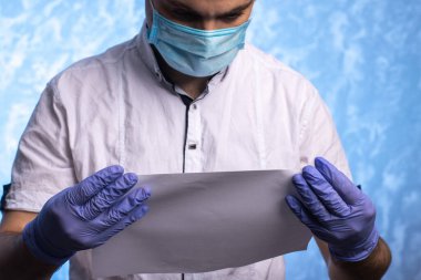 Tıbbi maske ve eldiven takmış bir doktor ya da ofis çalışanı elinde belgeler tutuyor. Yakın plan. mesaj için yer. Karantinaya alınmış hijyen kuralları. enfeksiyon koruması.