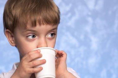 Küçük bir çocuk çevre dostu tek kullanımlık mısır nişastasından su içiyor. Çevre dostu kavram. Yakın plan portre. ev konforu.