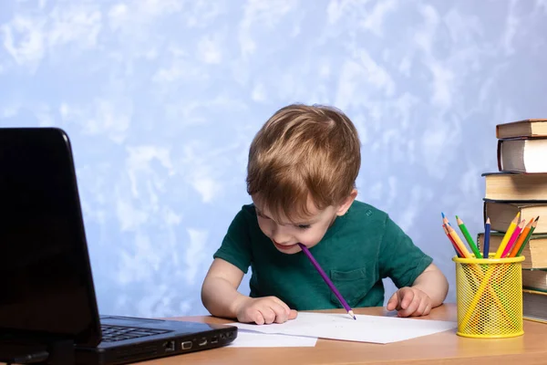 머리를 숙이고 연필을 깨물었다 아이는 숙제를 있습니다 근처에 노트북 온라인에서 — 스톡 사진