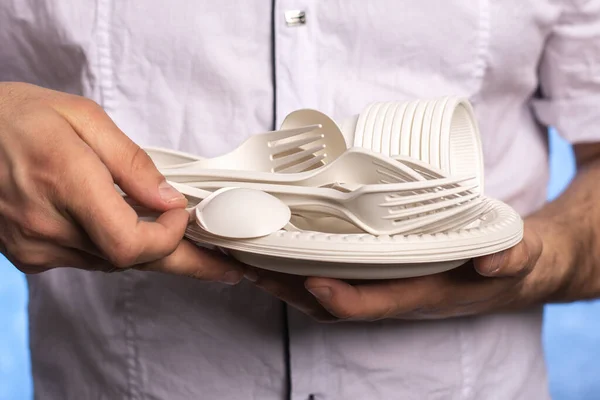 biodegradable disposable tableware in male hands. forks, spoons, cornstarch plates. Replacing plastic with environmentally friendly materials. the waiter carries appliances.