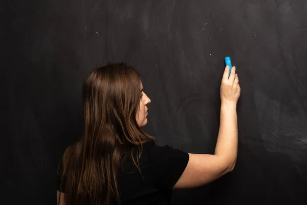 Ένα Νεαρό Κορίτσι Στέκεται Δίπλα Έναν Πίνακα Και Γράφει Κιμωλία — Φωτογραφία Αρχείου