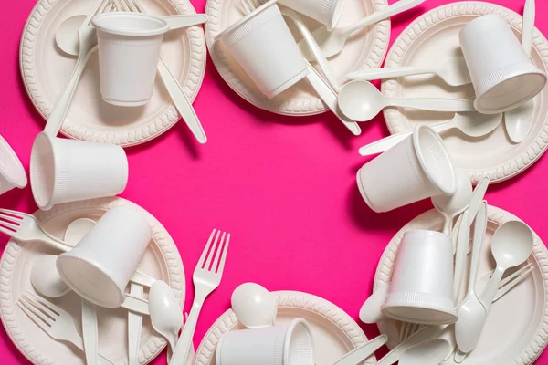 sets of disposable spoons, forks, plates and glasses of corn starch on a pink background. biodegradable dishes. environmentally friendly isolate. replacement of plastic with modern biomaterials