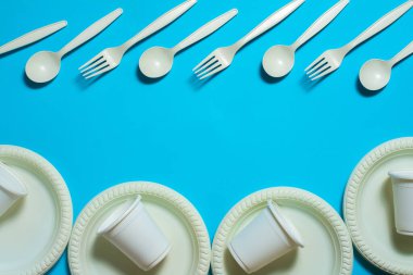 Tek kullanımlık kaşıklar, çatallar, bardaklar ve mavi arka planda mısır nişastası. Çevre dostu yemekler. İzole et. Plastik yerine ekolojik malzemeler. metin için yer