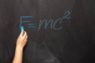 Einstein 'ın teorisinin fiziksel formülü bir tahtaya mavi tebeşirle yazılmıştır. FMC2 sınıfta bir fen öğretmeni veya öğrenci tarafından yazılır..