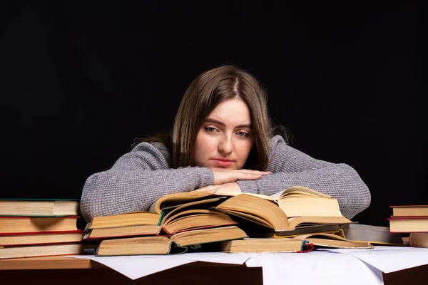 若い女学生が悲しい表情の本でストーマの後ろに座っている 試験準備だ 距離学習の難しさ — ストック写真