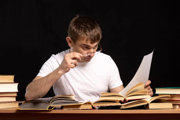 Joven Estudiante Sienta Una Mesa Con Libros Sobre Fondo Negro — Foto de Stock