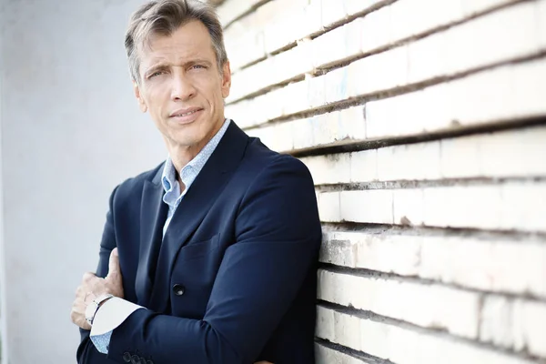 40-50 yaşlarında, mavi takım elbiseli, dışarıda poz veren bir iş adamı.