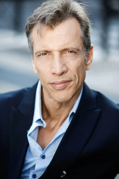 45-50 yaşlarındaki iş adamı kameraya kendinden emin bakıyor.