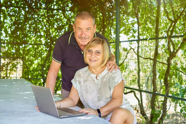 Çevrimiçi sörf yapan üst düzey çiftler, aktif yaşlılar ve yeni teknolojilerle etkileşim kavramları olan doğal ve yeşil bir konumda bilgisayar kullanıyorlar.