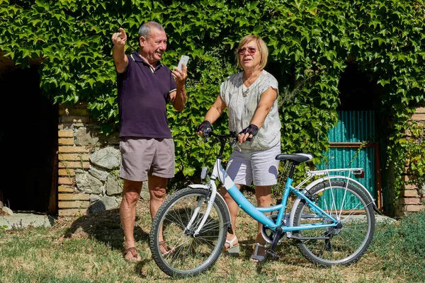 Senior couple looking for direction in bike trip in countryside outdoor location - Concept of active elderly and interaction with new technologies Royalty Free Stock Photos