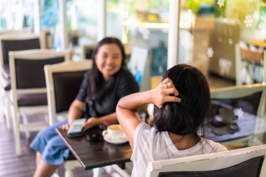 İki Asyalı kadın konuşmak ve kafede kahve içme keyfini çıkarın